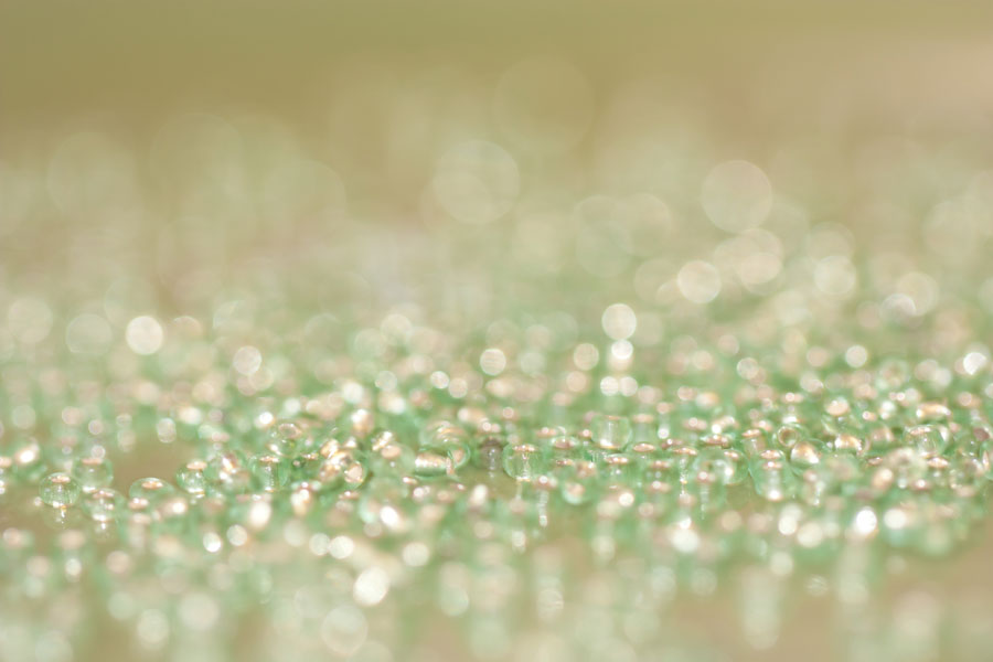 Worker Beads – Thumbnail of a texture of pale green glass beads & reflected bokeh bubbles